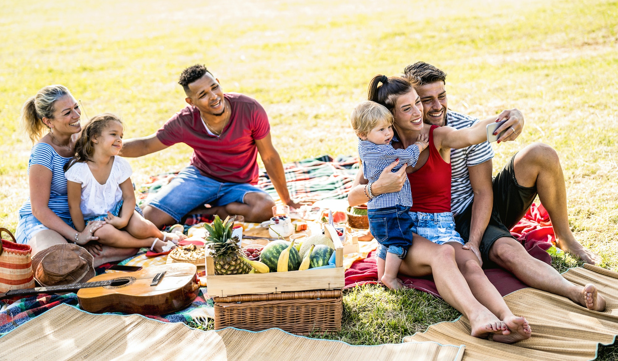 Happy multiracial families taking selfie at pic nic garden party